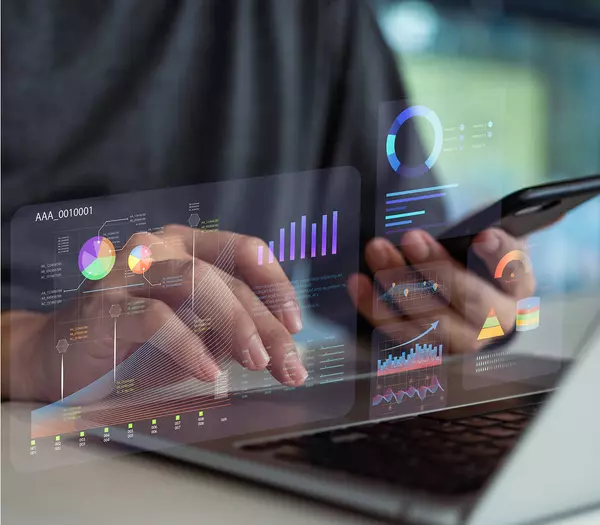 Person using laptop and phone overlaid with holographic elements
