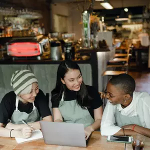 Three people sitting at table in cafe with laptop