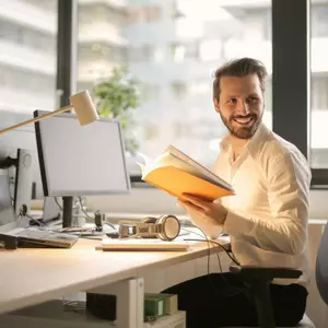 Man holding book sitting at desk